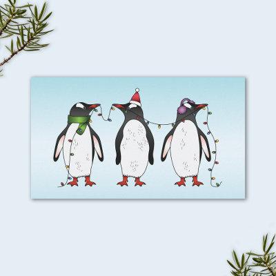Three Festive Christmas Penguins On Light Blue